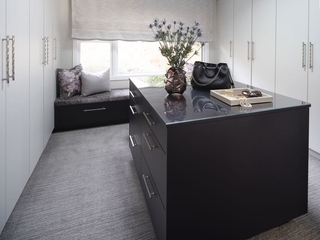 custom cabinets in walk-in closet with island and window seating