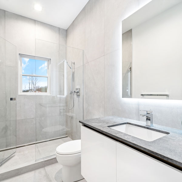 single vanity with backlit mirror and shower in luxury bathroom